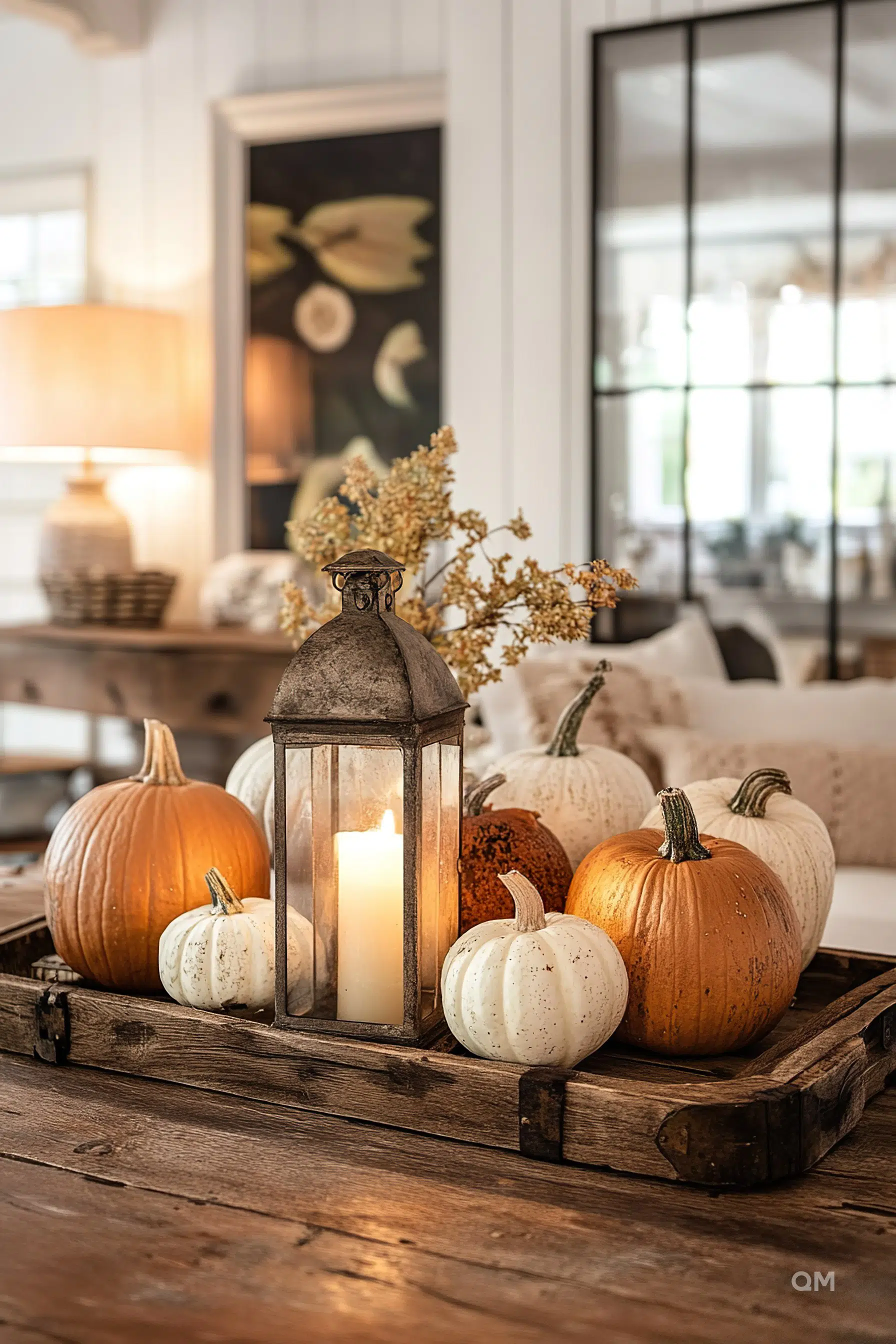 A cozy autumnal setting with pumpkins of varying colors alongside a lit candle inside a rustic lantern on a wooden table.
