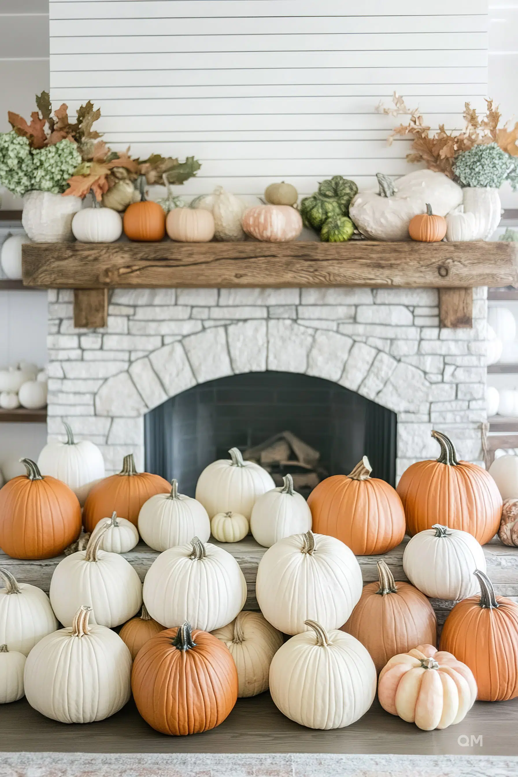 A cozy autumnal hearth adorned with a collection of orange and white pumpkins, some on the mantel among dried leaves and blooms.