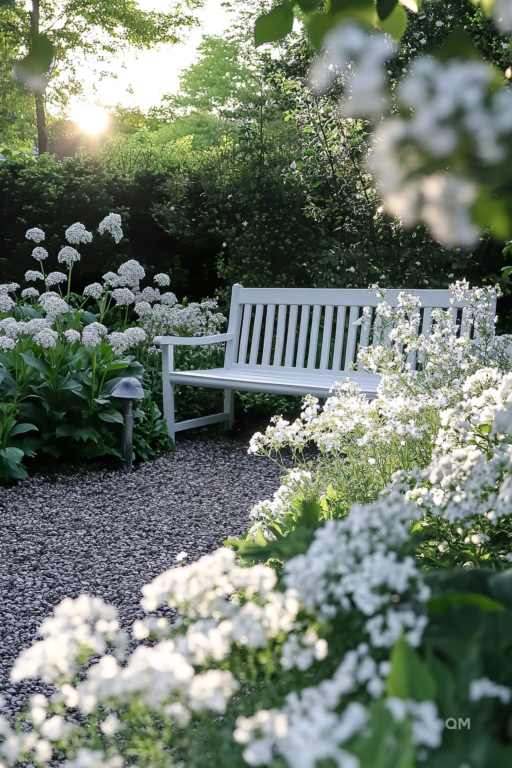 A white bench surrounded by blooming white flowers in a tranquil garden at sunset.