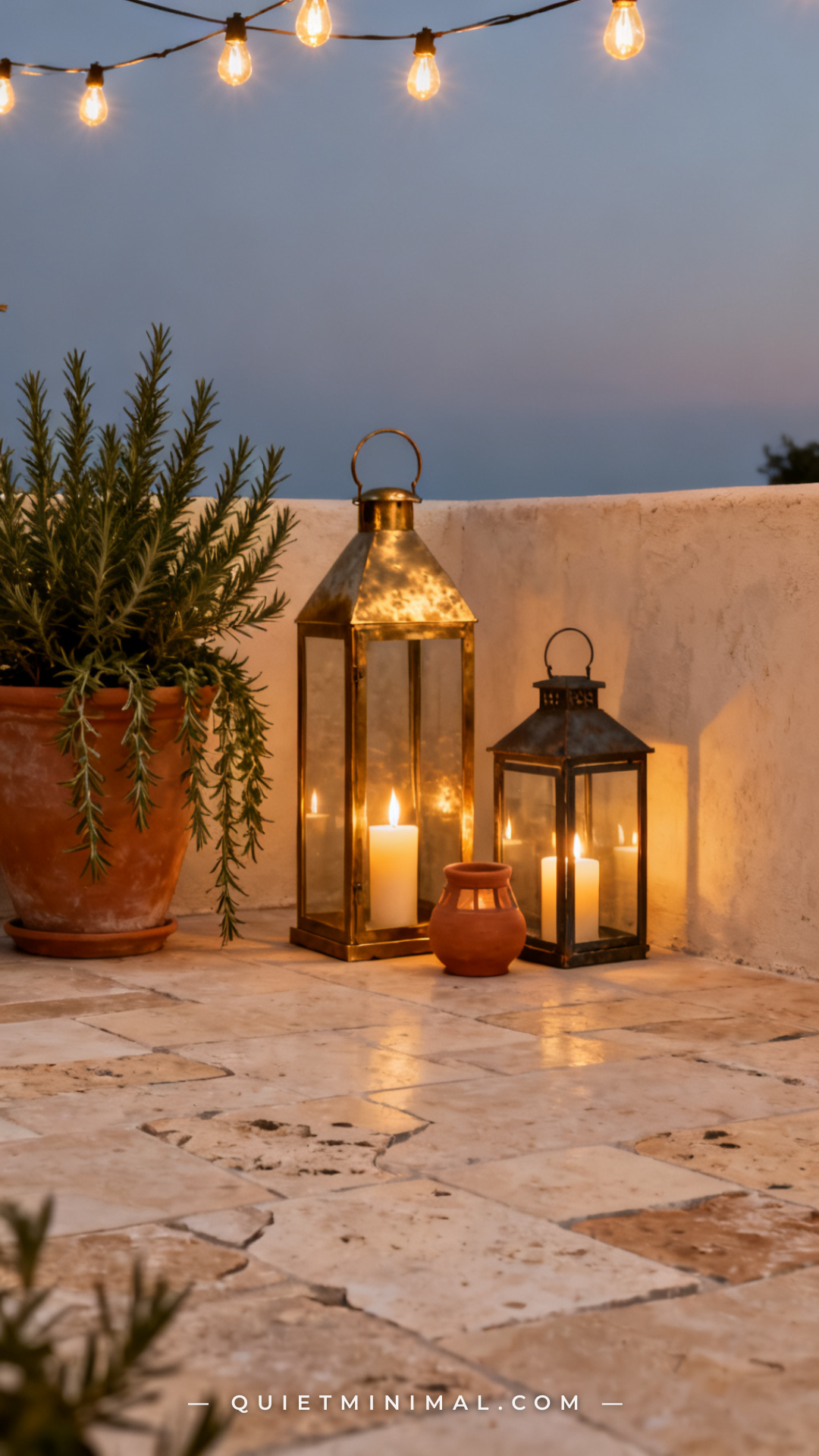 A wide establishing shot of a patio floor at dusk showing a collection of lanterns at ground level arranged near the bas