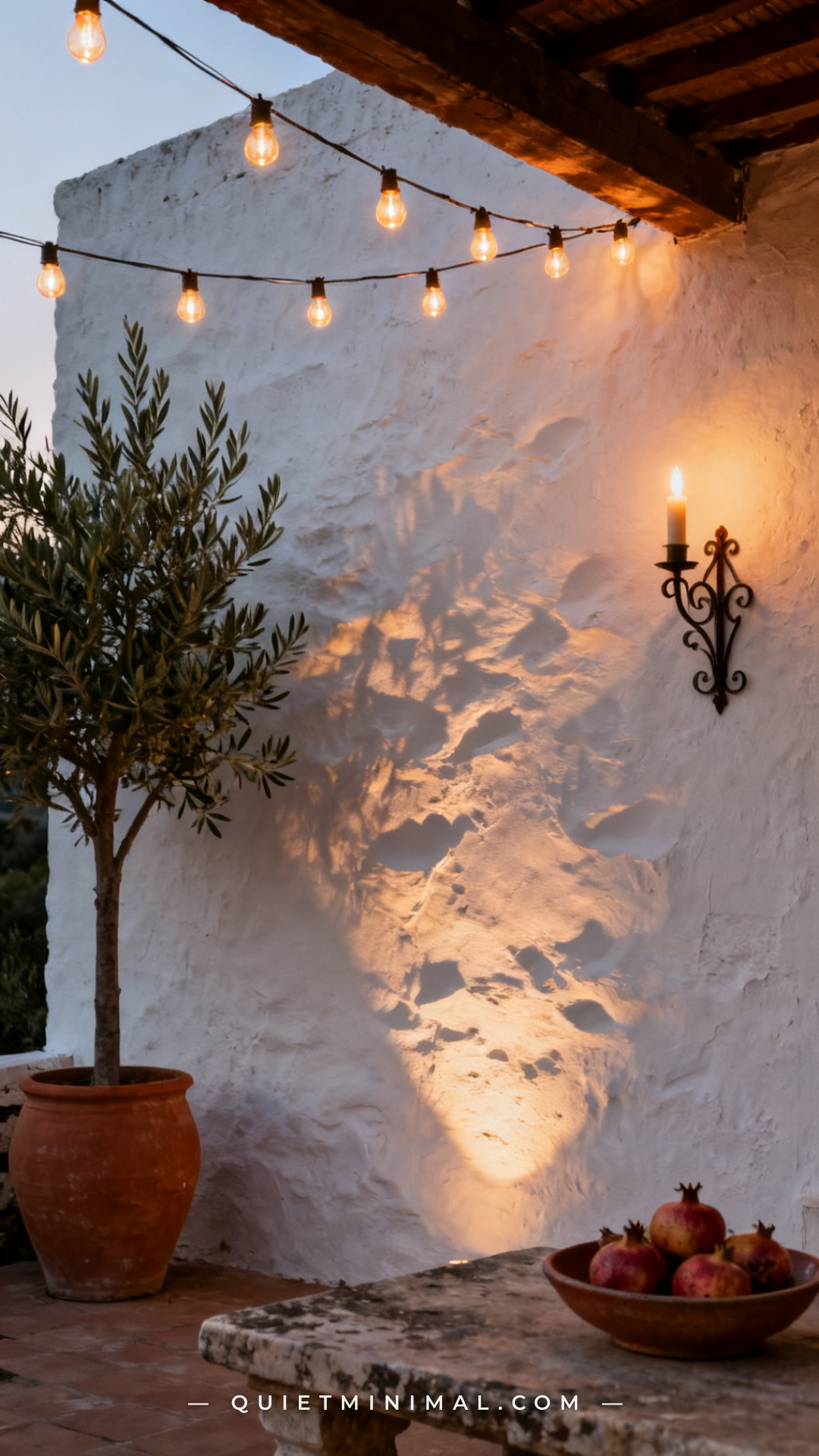 A wide establishing shot of a patio with a thick whitewashed stucco wall serving as the dominant backdrop