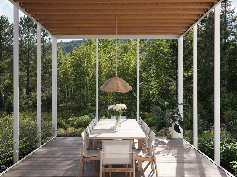 open-sided pergola outdoor dining room with long teak table, white sling chairs, woven rattan pendant, cedar ceiling, de