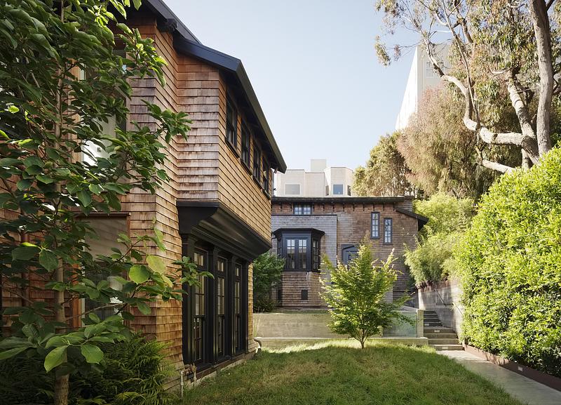 rear garden view of cedar shingle house showing two-story original volume and lower addition, black-framed French doors