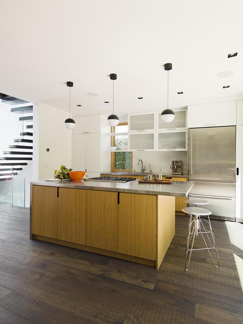 kitchen with bamboo-faced island, stainless steel countertop and refrigerator, white flat-front upper cabinets with fros