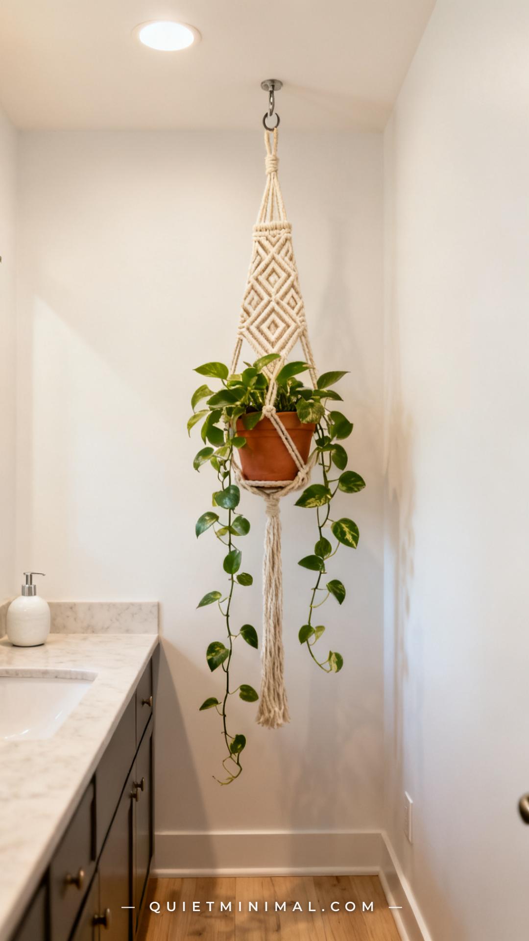 A vertical photograph captures a wide bathroom interior with a macramé plant hanger suspended from a ceiling hook near t