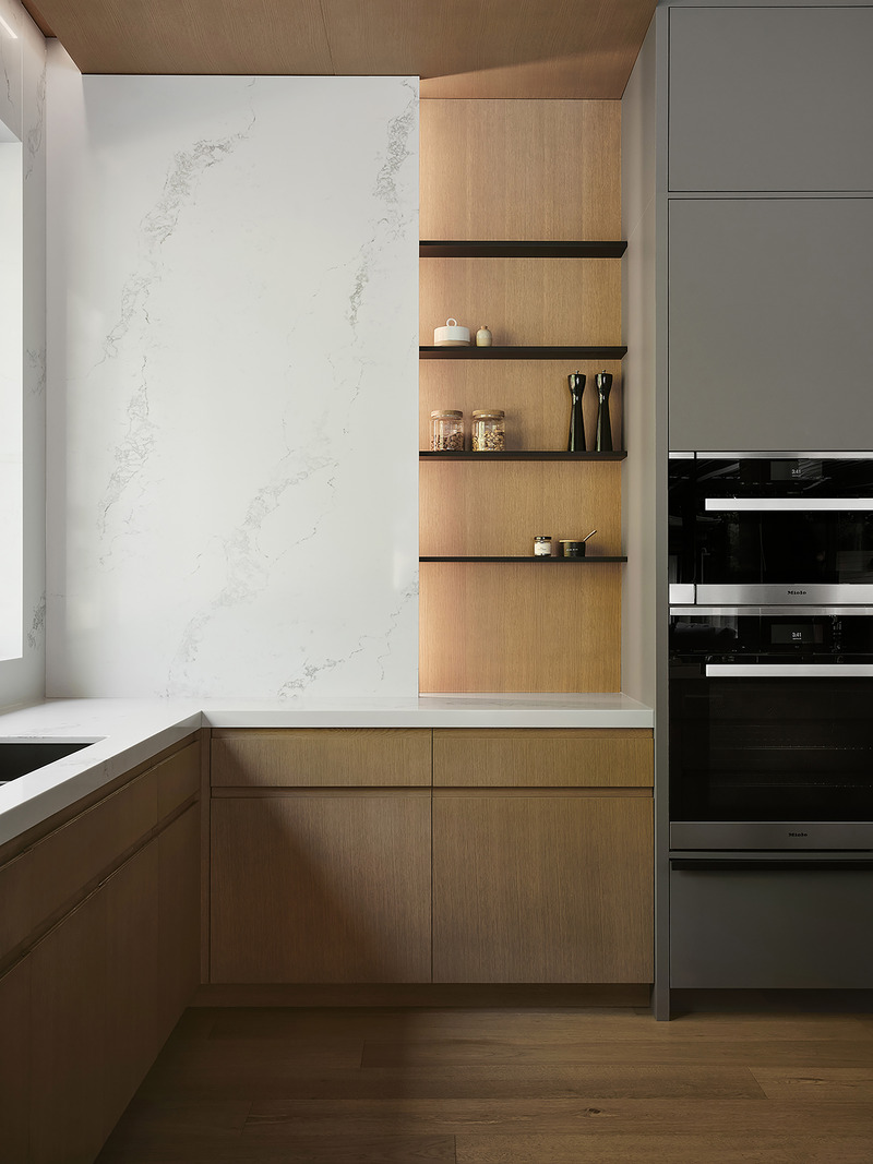 kitchen alcove detail with backlit natural oak open shelving holding glass jars and ceramics, white veined stone backspl