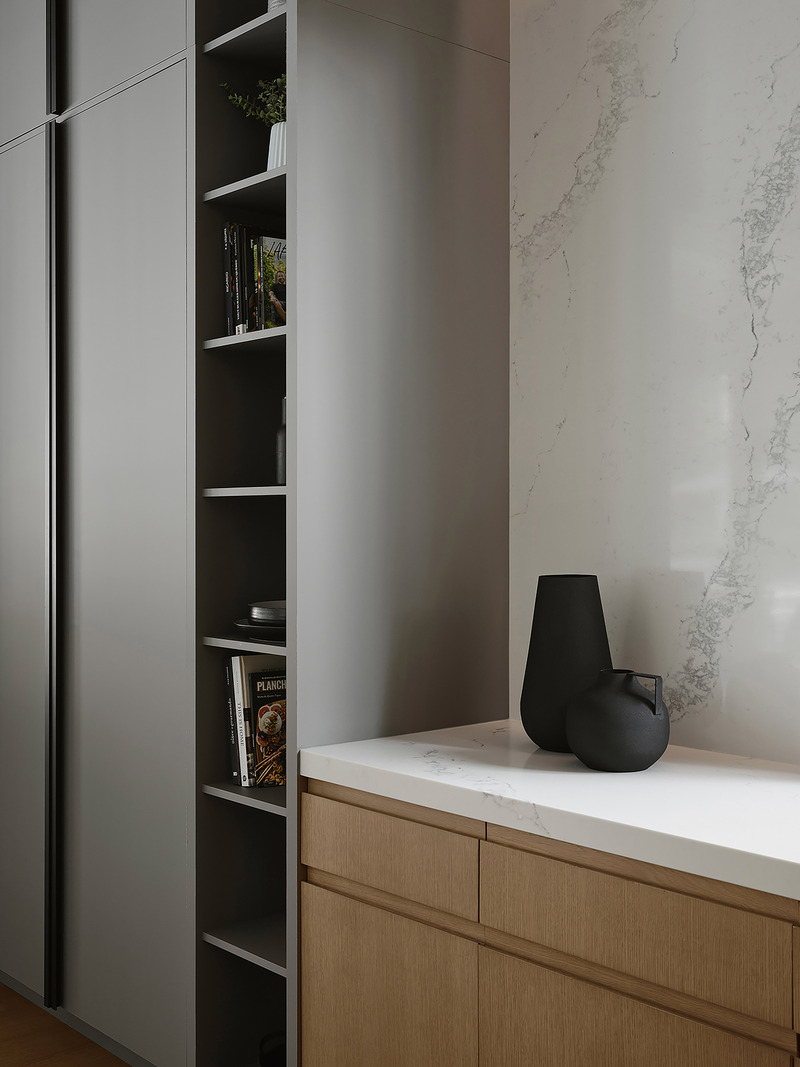 kitchen counter corner with grey flat-front tall cabinetry, narrow open grey shelving holding cookbooks and ceramics, wh
