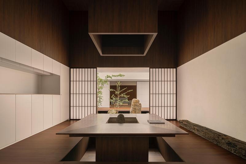 double-height dining and kitchen area with dark walnut wood-clad walls and ceiling, square smoke hood overhead, shoji ri