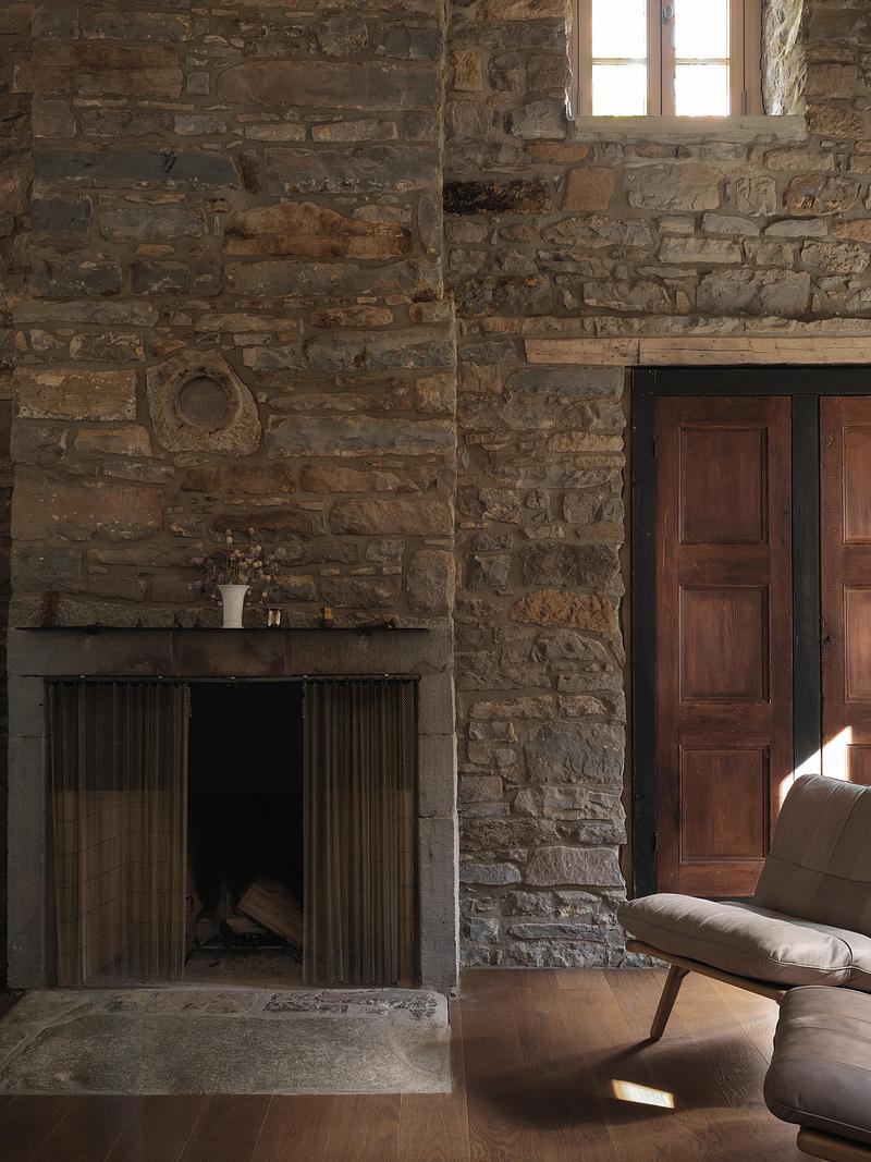 main living room fieldstone fireplace with dark stone mantel, bronze chain-mail curtain, single small ceramic vase, orig