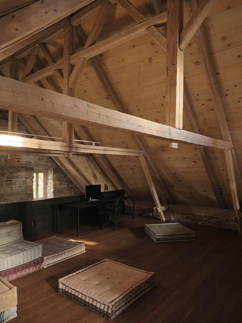 attic loft under exposed full-pitch timber truss structure with pale pine boards, dark hardwood floor, faded rose and sa