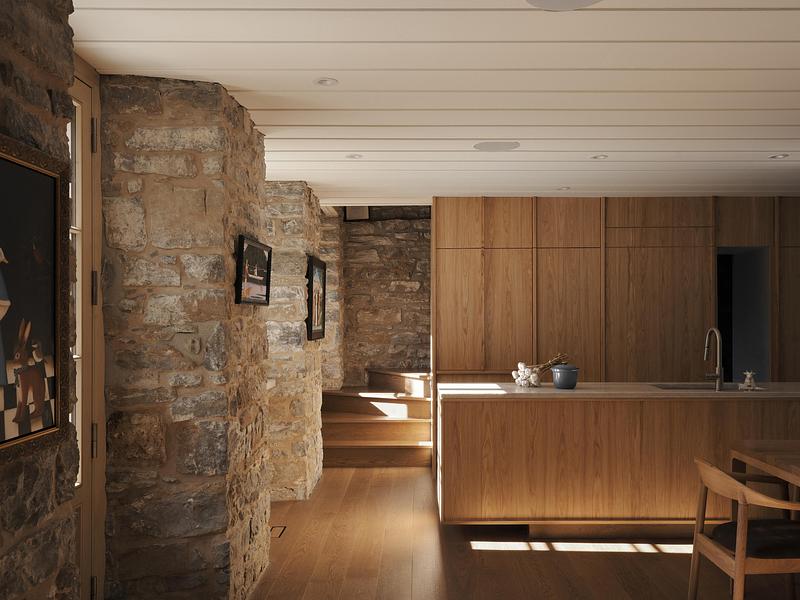view from old stone hallway into new oak kitchen with curved original stone wall at left, small painting hung on stone,