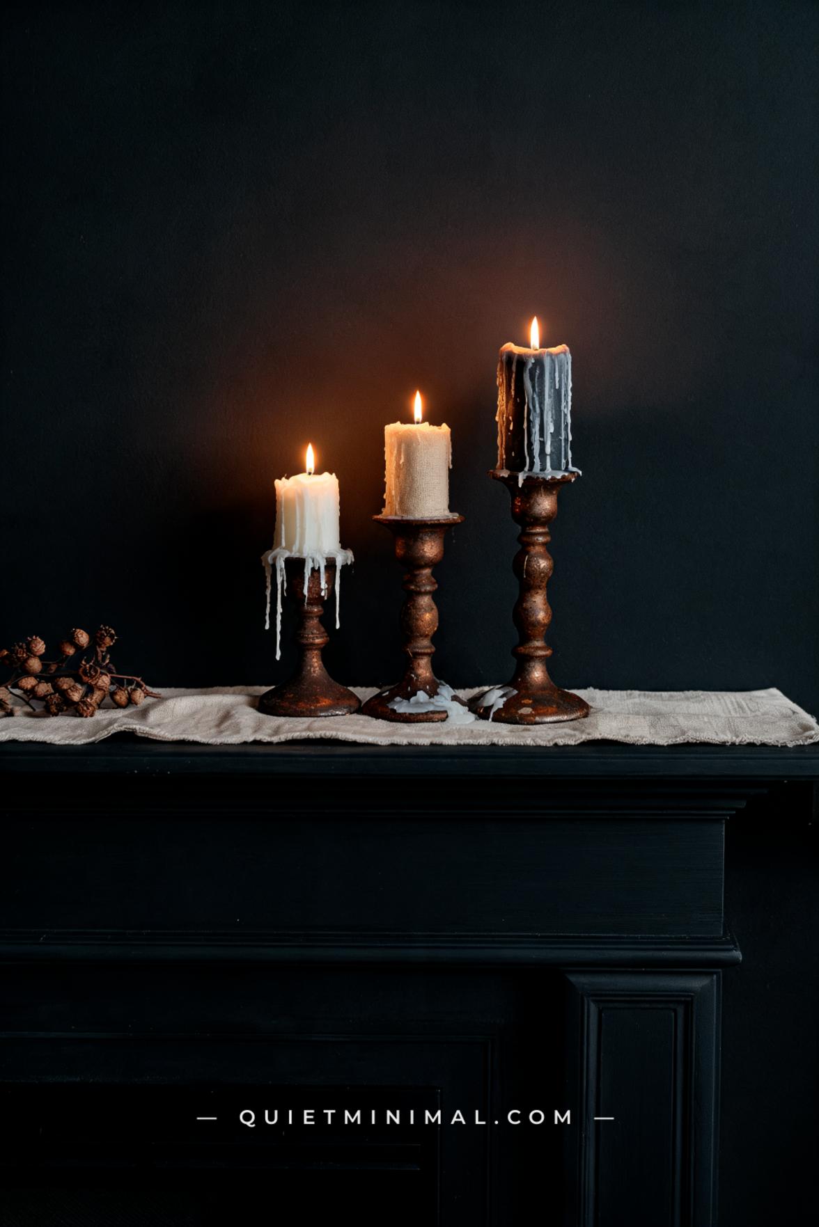 A medium-wide composition of a fireplace mantel showing three aged iron candle holders clustered together at staggered h