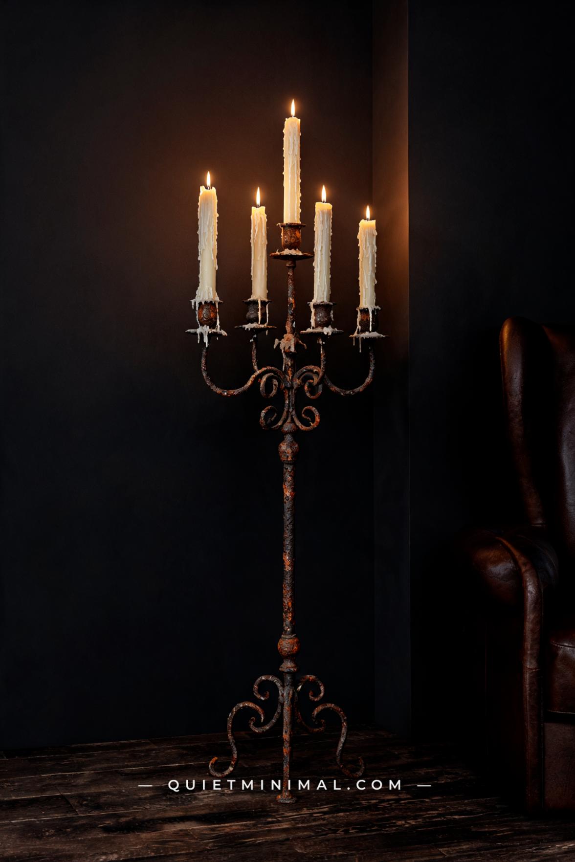 A vertical photograph captures a reading nook corner with a floor-standing iron candelabra holding five taper candles at