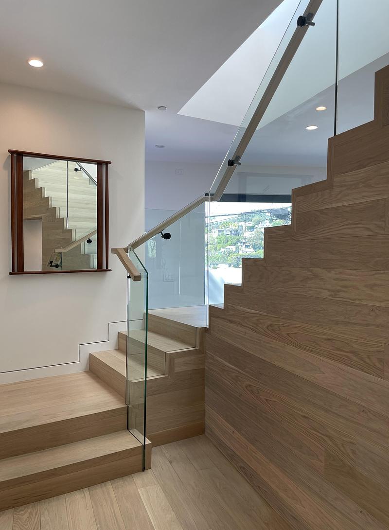 mid-level stair landing with white oak cladding on stringer, full-height glass balustrade and slim oak handrail, small d