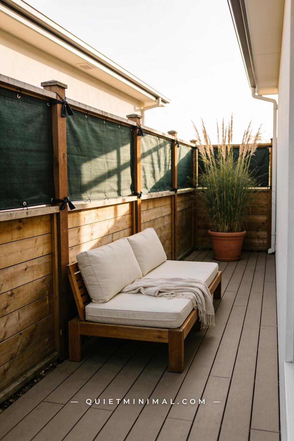 A vertical photograph captures a long wooden privacy fence along the edge of a patio