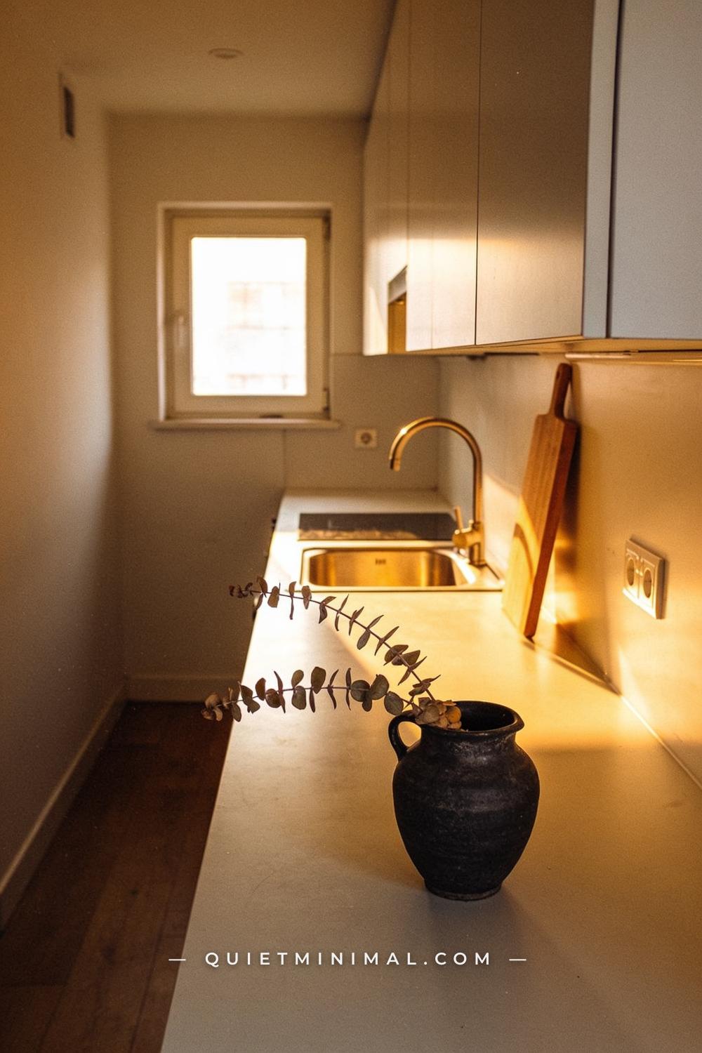 A wide establishing shot from the far end of a small apartment kitchen