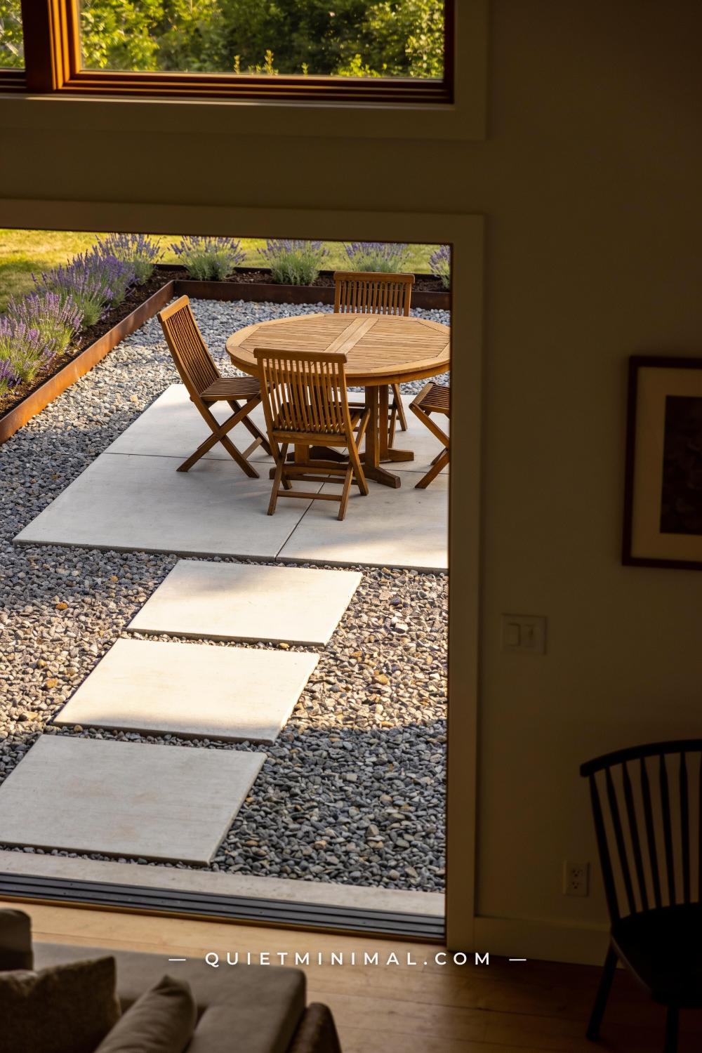 A vertical photograph of an outdoor dining area where large square concrete pavers form a defined dining platform
