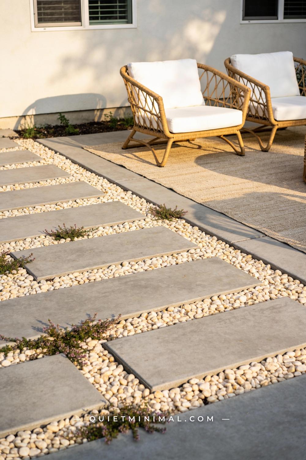 A vertical photograph of a backyard patio where wide-joint concrete pavers are laid with 2-inch gaps between each paver