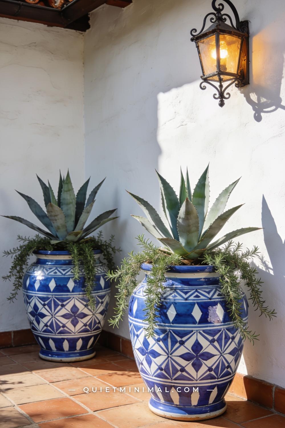 A wide shot of a Spanish Revival patio corner anchored by two large Talavera ceramic pots planted with agave and trailin