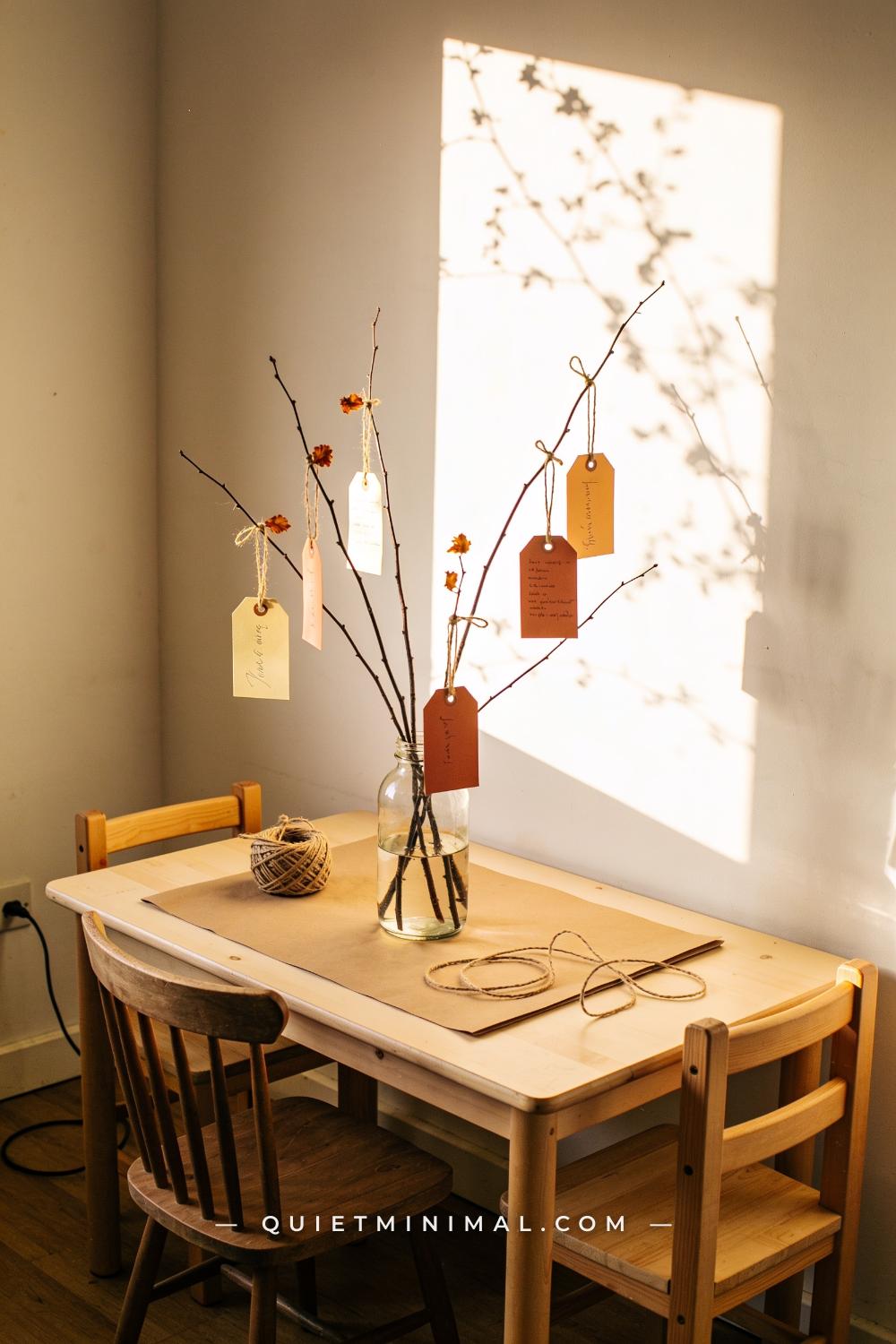 A wide establishing shot from a corner view of a small dining space showing a low kids table with a central glass jar va
