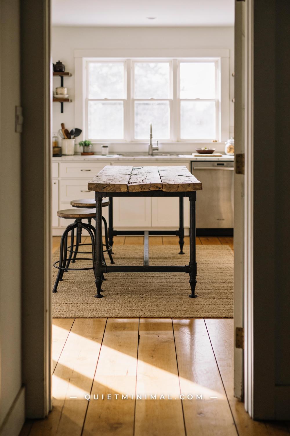 A wide establishing shot of a wabi-sabi kitchen taken from a doorway