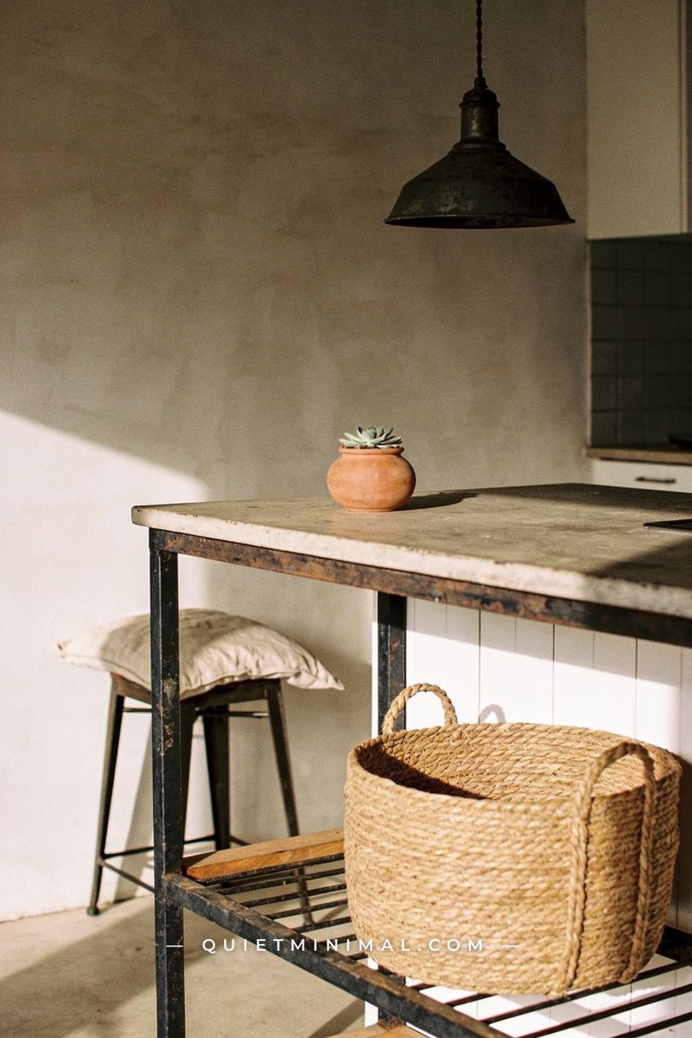 A medium-wide establishing shot of a wabi-sabi kitchen island showing the island top in the middle distance with a soft